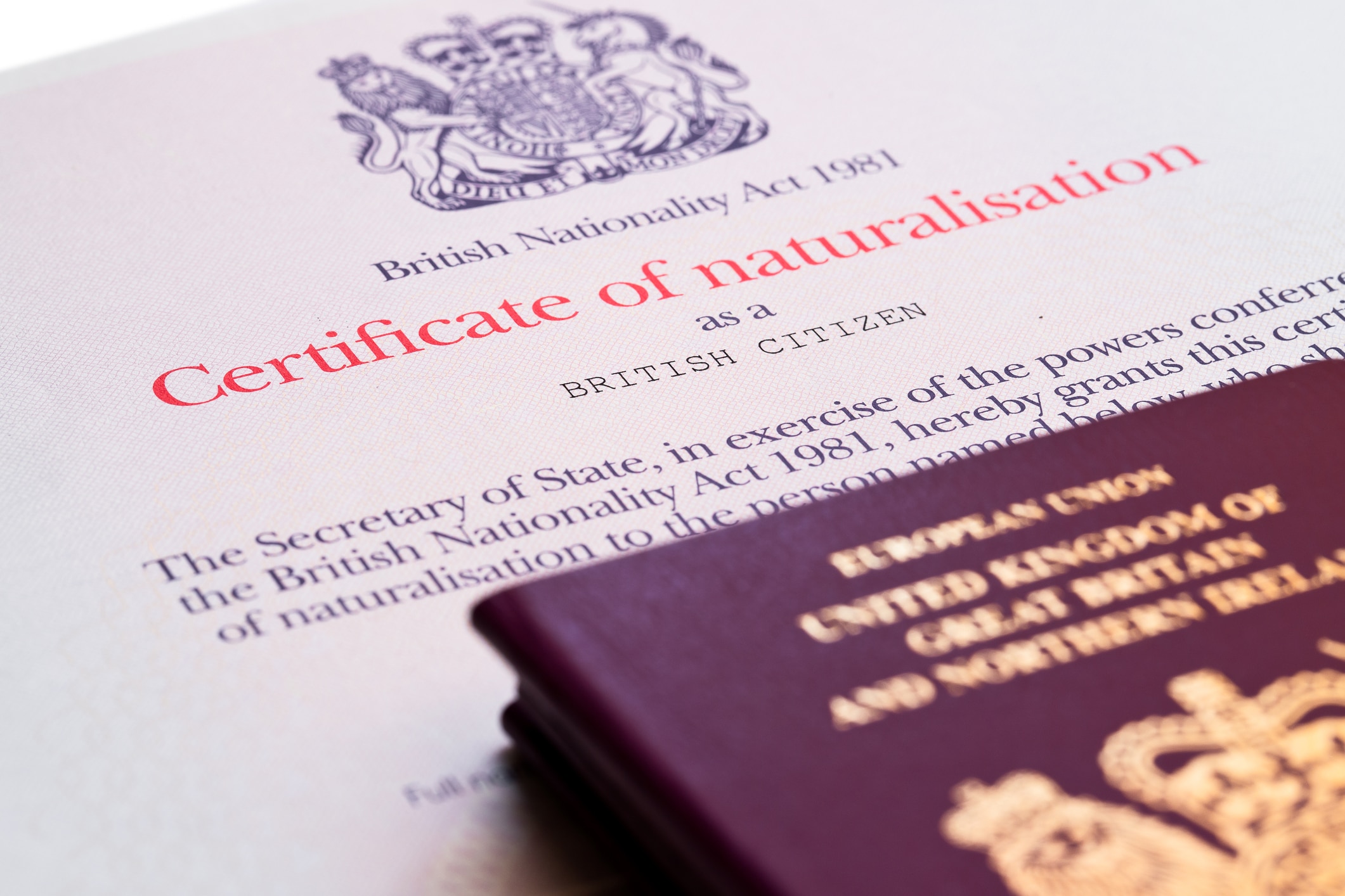 A British certificate of naturalisation, required to apply for British citizenship, on top of a United Kingdom passport.